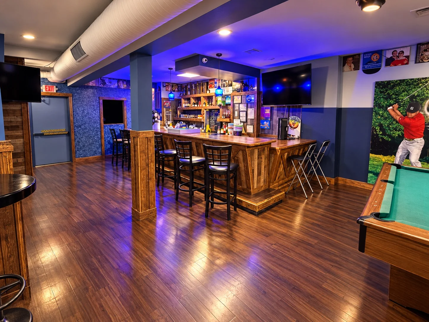 Blue Hills Cafe interior with a wooden bar, bar stools, blue lighting, televisions, and a pool table